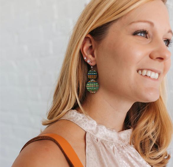 Woman wearing two toned brown fleur de lis round genuine leather earrings