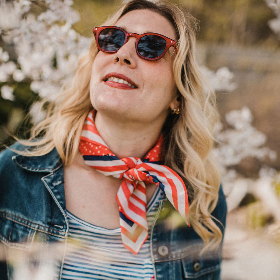 Woman wearing Molly Hatch red white and blue flower patch bandana scarf around neck with jean jacket